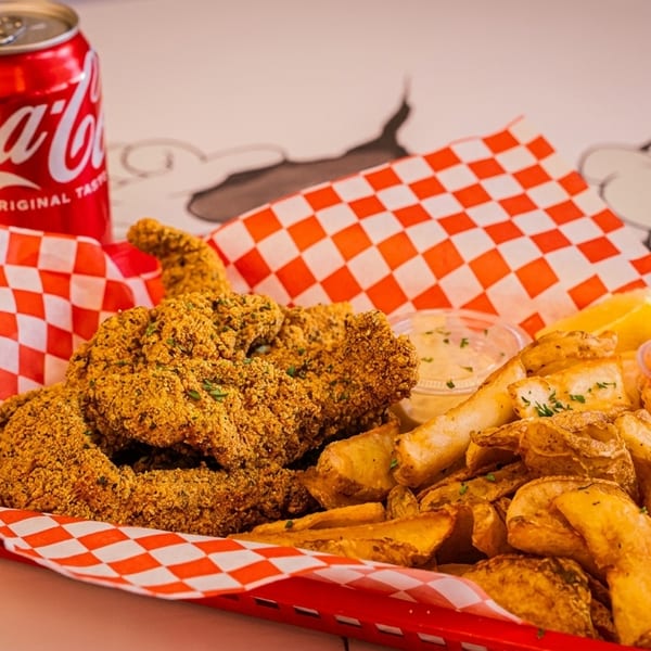 Fried fish and potato wedges in a red basket with a Coca-Cola can and dipping sauces.