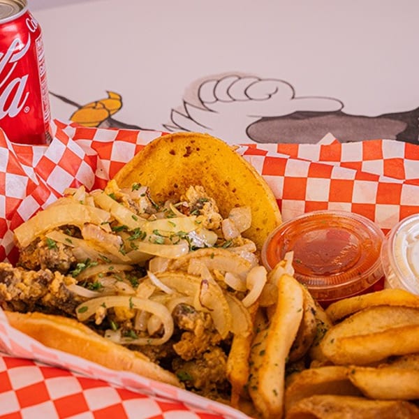 A basket of fried food with onions, fries, a golden pastry, two sauces, and a Coca-Cola can.